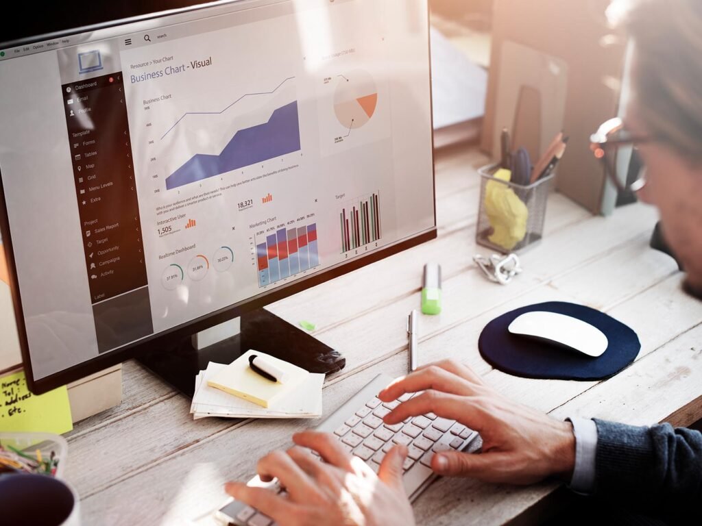 Person analyzing Understanding the Importance of PPC: business performance charts and marketing data on a desktop computer in a modern office setting."
